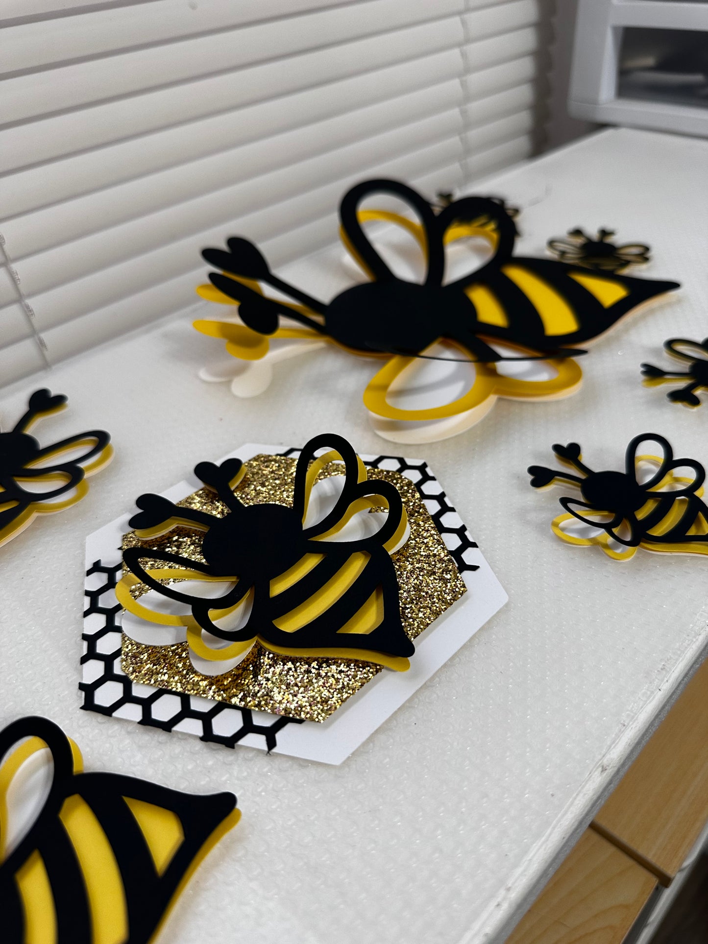 Bee-lieve handmade honeybee paper banner with glitter accents in black, yellow, and gold
Close-up of layered cardstock honeycomb details on Bee-lieve banner
Bee-lieve banner displayed as party décor with ribbon tassels and bead accents
Honeybee banner hanging in a nursery or classroom setting
Bee-lieve banner styled on a tiered tray for home décor
Full view of Bee-lieve honeybee garland banner for bee-themed celebrations